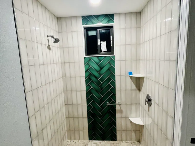 Shower with a green herringbone accent and centered valve
